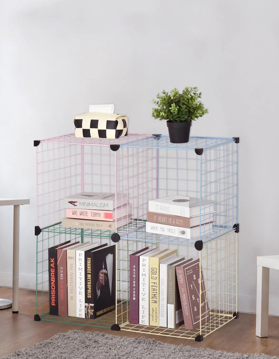 Estante con rejillas metálicas de colores pastel con forma cuadrada. En su interior hay libros de colores.