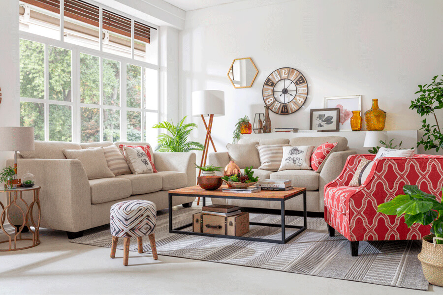 Sofá bajo la ventana Un living moderno con 2 sillones de 2 cuerpos de color neutro y un sofá pequeño de color rojo con diseño, alrededor de una mesa de centro