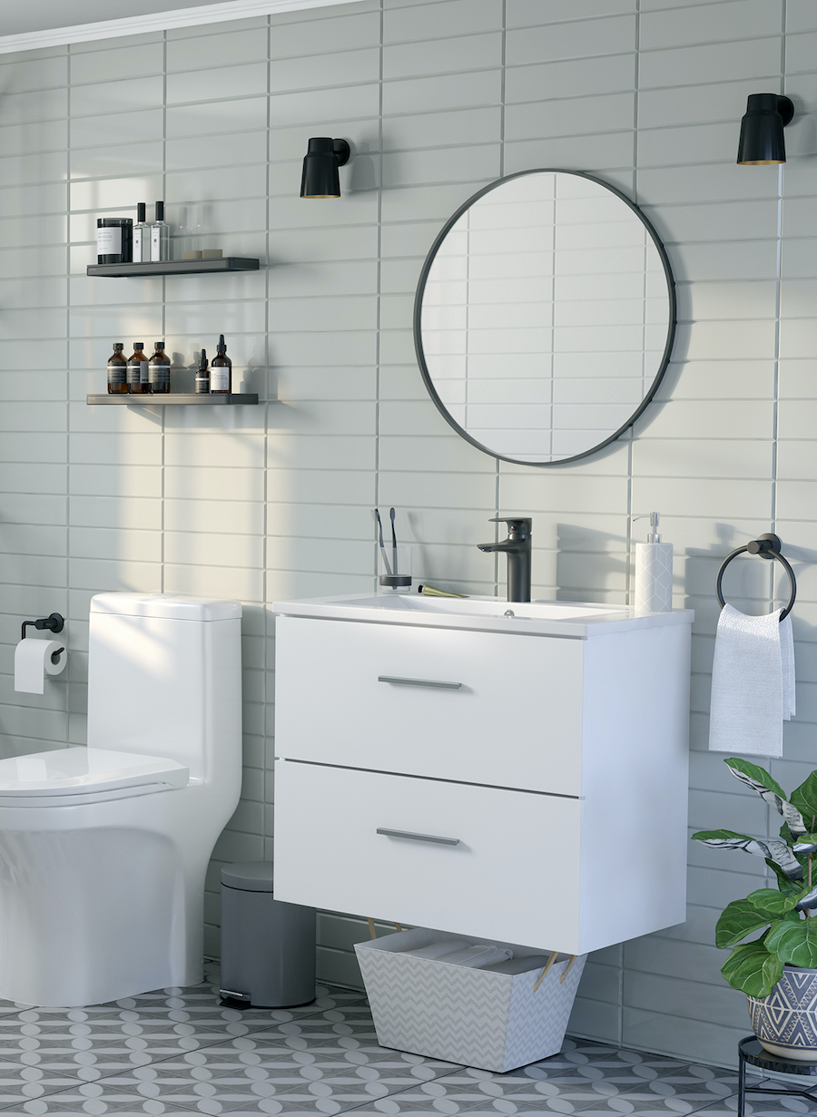 Baño pequeño con cerámica en color verde pastel, mueble vanitorio y WC blancos, espejo redondo con marco negro y grifería negra. También hay 2 repisas negras que sostienen artículos de aseo e higiene.