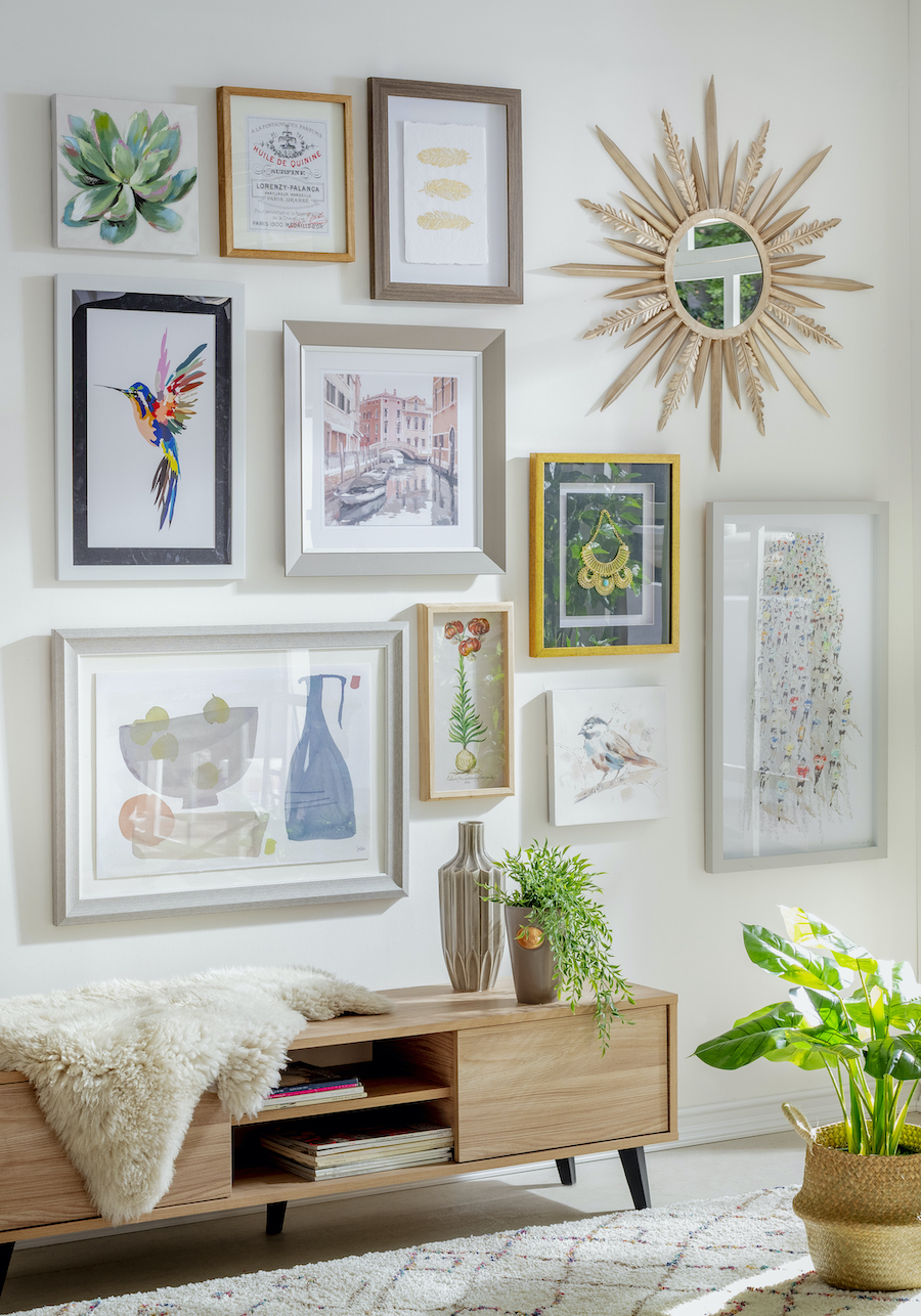 Pasillo estrecho con mueble de madera. Sobre él hay un gran muro galería con cuadros de diferentes tamaños y diseños, de muchos colores y estilos.