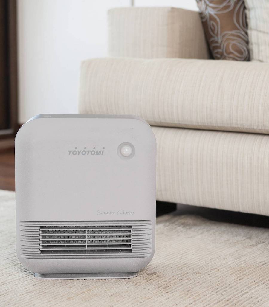 Termoventilador eléctrico blanco, disponible en Sodimac. Es pequeño y curvo y está ubicado en el suelo sobre una alfombra blanca.