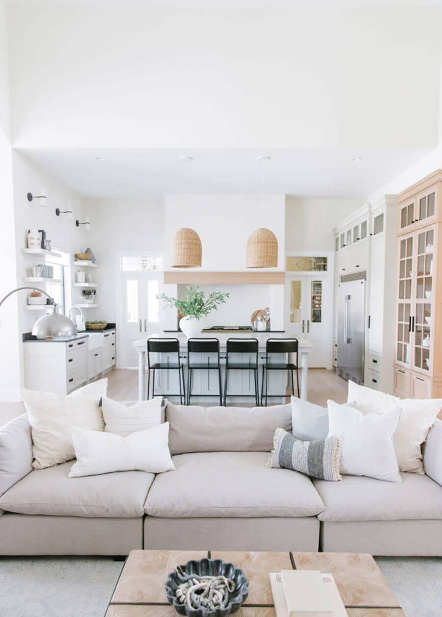 Una cocina integrada moderna de colores neutros con una isla de cocina y pisos altos negros