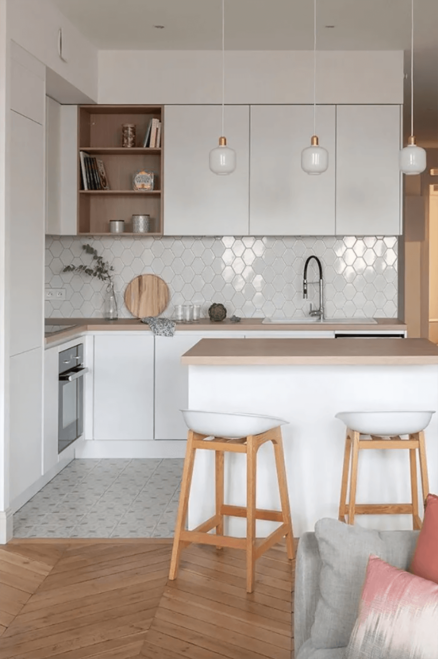 Una cocina abierta en colores blancos y neutros con una isla de cocina central con cubierta de madera