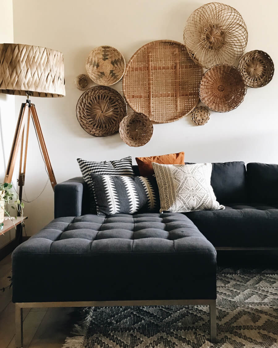Un living moderno con un sillón negro grande y canastos de mimbre como decoración de living