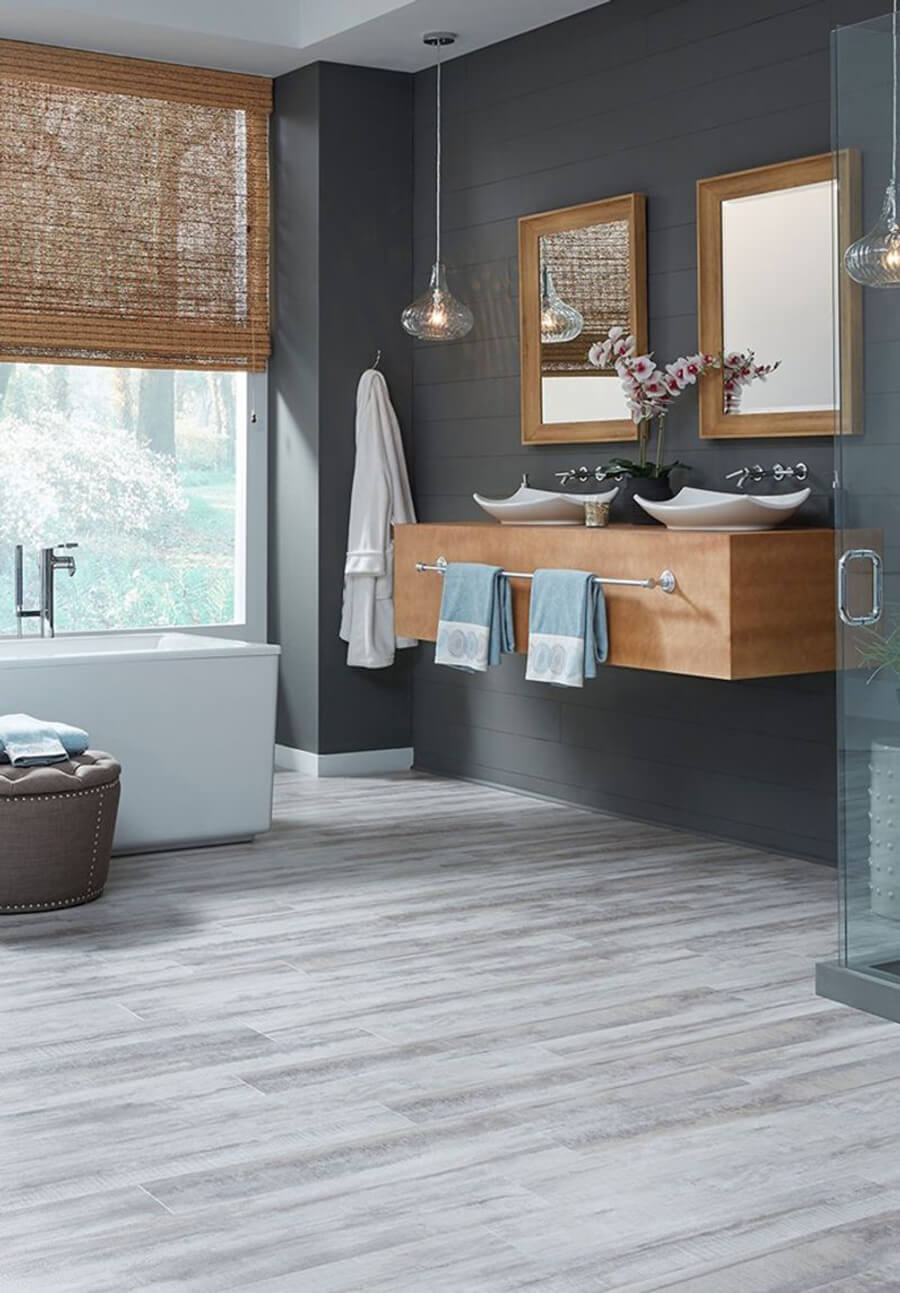 un baño moderno con piso laminado o vinílico, y las paredes de color plomo.