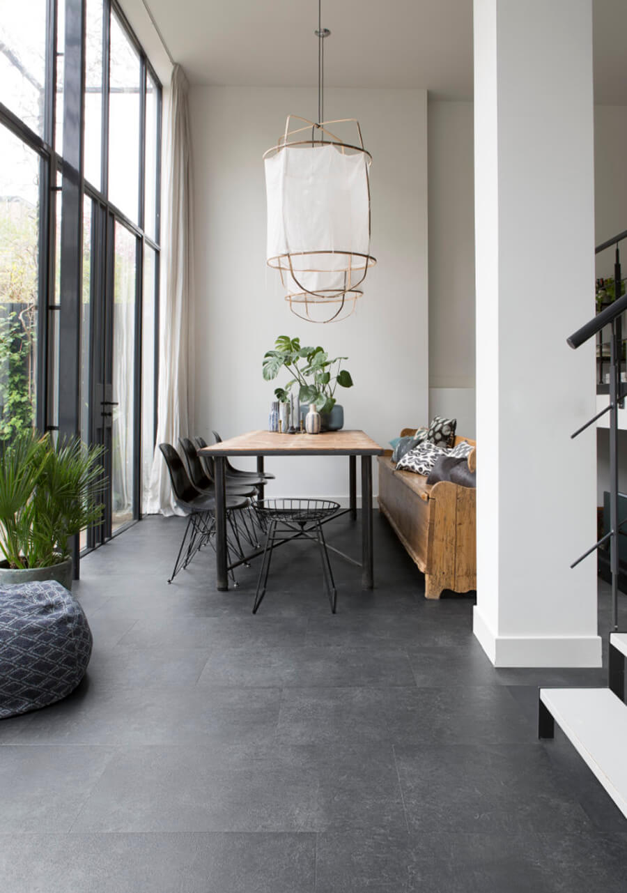 un comedor con piso de porcelanato gris plomo, con un juego de comedor de base y sillas de color plomo.