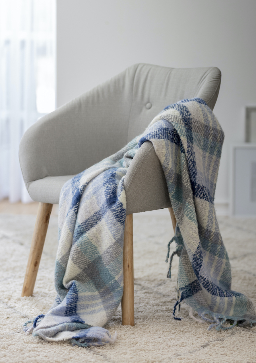 Sitial gris con manta cuadrillé en color blanco y azul.