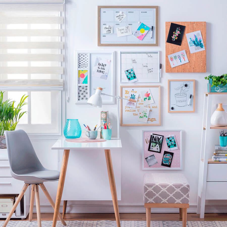 un espacio con una pequeña mesa, una silla y un taburete, con paredes blancas en donde hay varias pizarras para organizar la casa con tareas y responsabilidades.