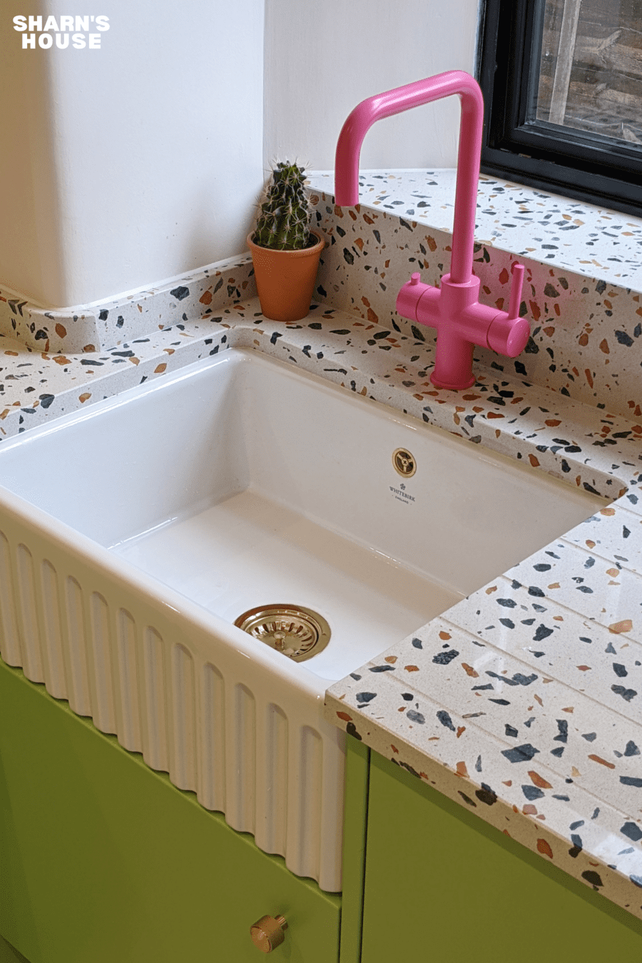 Lavaplatos con cubierta de terrazzo multicolor, mueble verde olivo y monomando rosa 