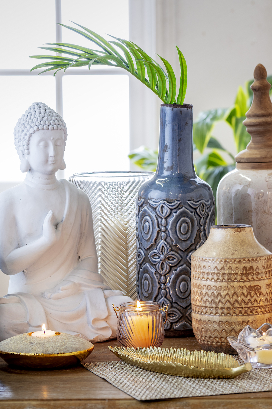 Detalle de unos jarrones, floreros, velas encendidas y una figura de Buda.
