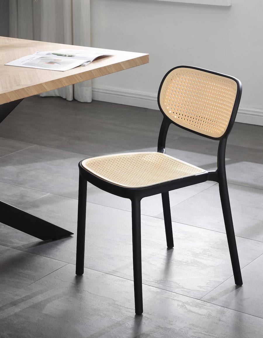 Detalle de una silla de comedor negra con detalles de ratán.