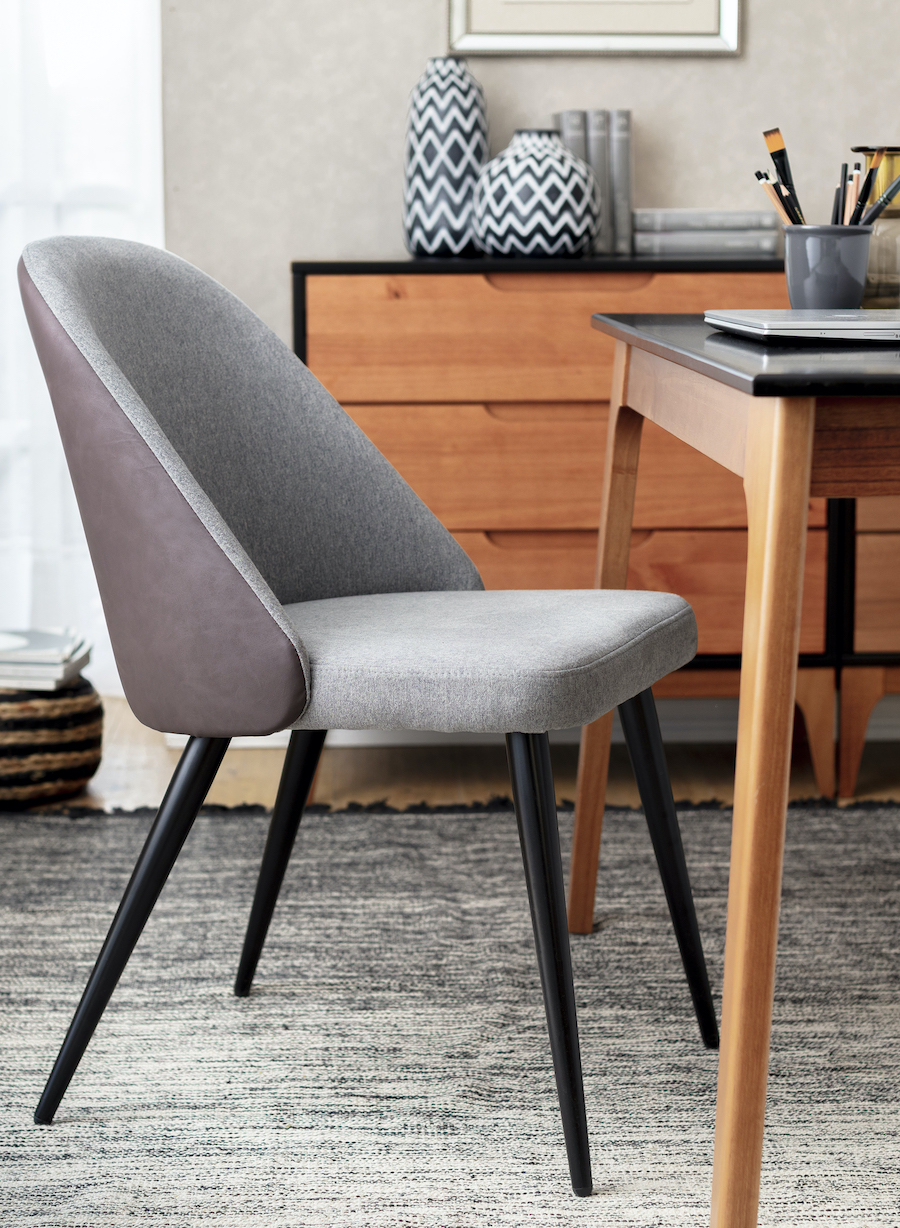 Silla gris con patas negras frente a una mesa de comedor de madera.