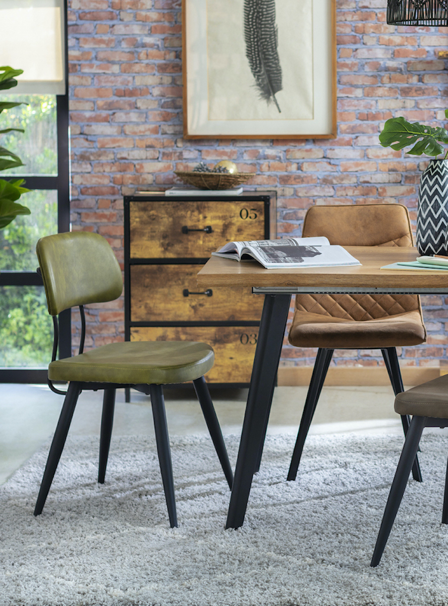 Comedor de estilo industrial con mesa y sillas de patas metálicas negras y tapiz de eco cuero. Están sobre un tipo de alfombra shaggy gris.