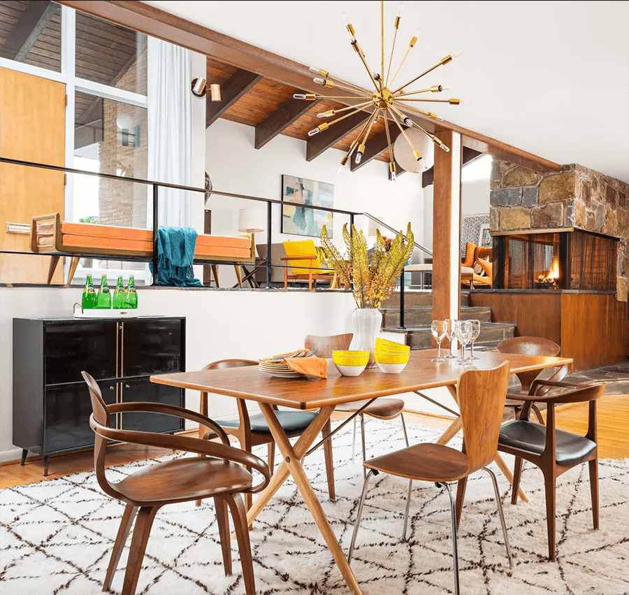 Un comedor decorado al estilo vintage moderno. Destaca el uso de la madera y la lámpara colgante.