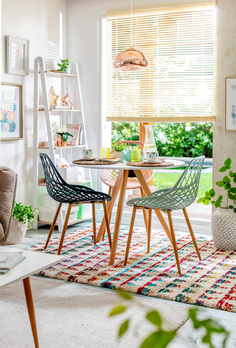 Mesa de comedor redonda con tres silllas de superficie decorada con diseño geométrico, persiana amarilla y repisa blanca