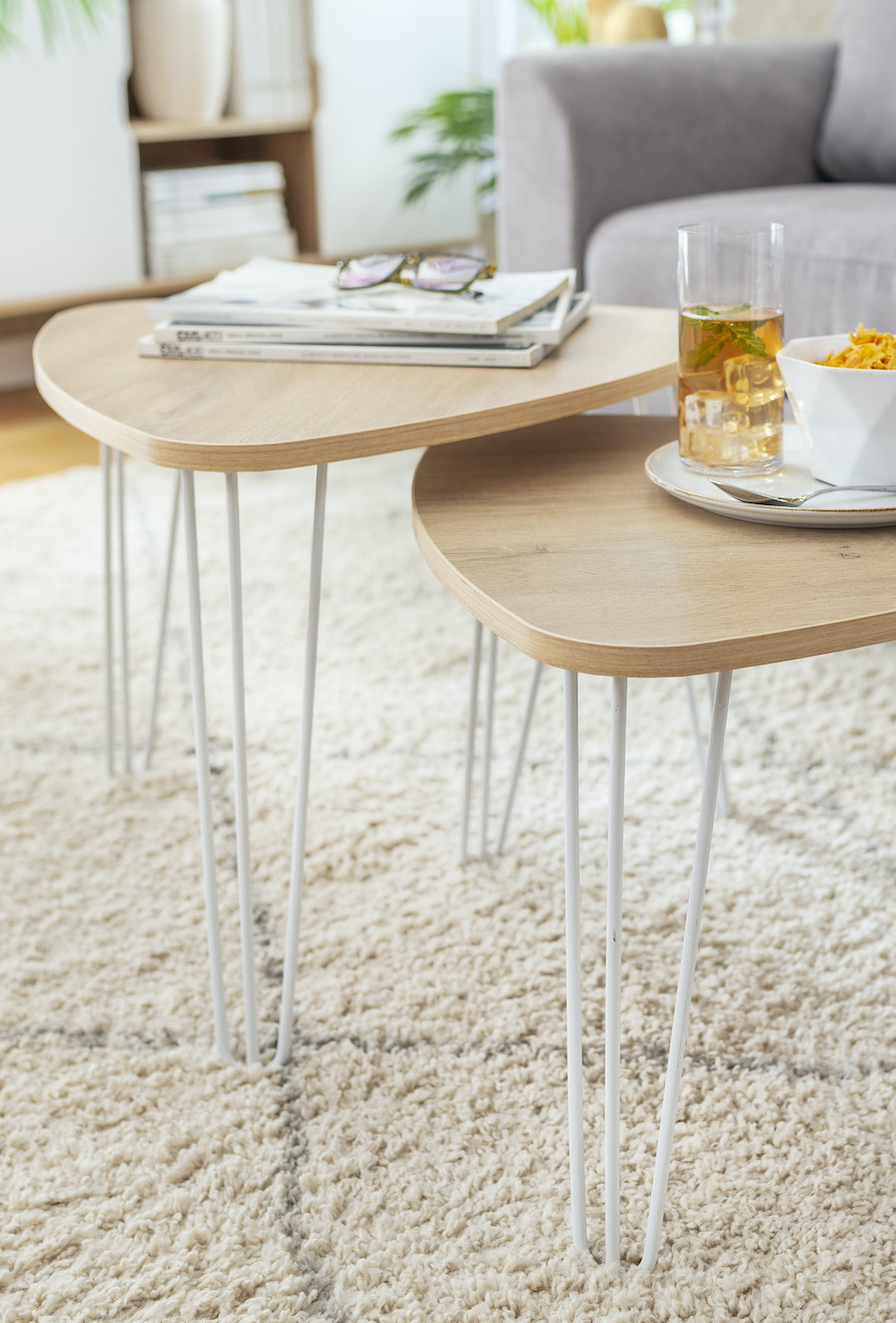 Set de mesas de centro de madera con patas metálicas, de estilo nórdico, sobre una alfombra blanca.
