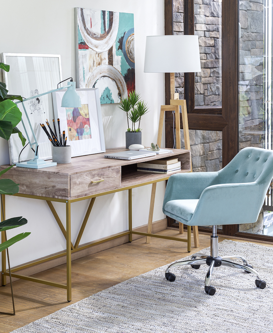 Escritorio de estilo nórdico con una silla con respaldo capitoné color celeste. Sobre el escritorio hay cuadros con ilustraciones, una planta y un lapicero. Al costado hay una lámpara de pie de estilo nórdico.