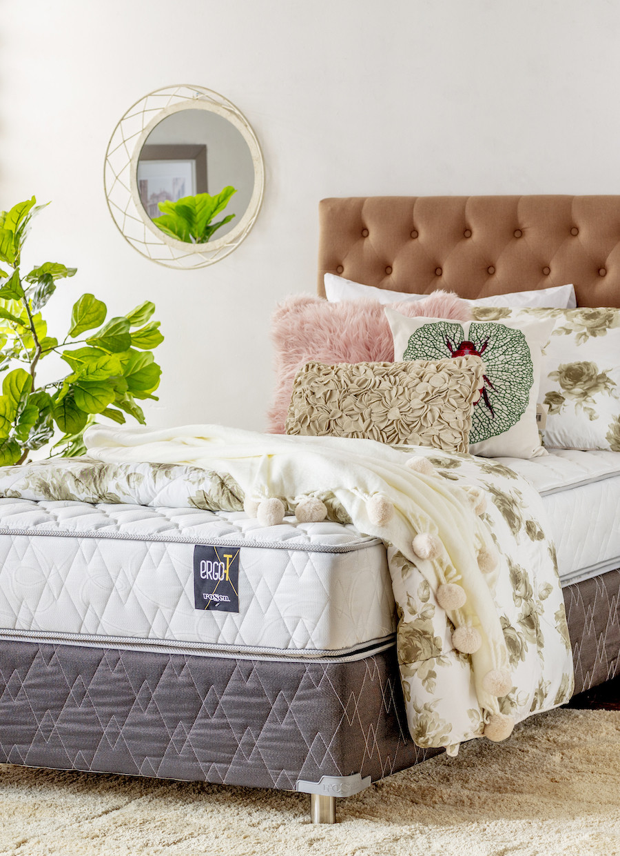 Cama de 1 plaza y media con respaldo capitoné café, colchón y ropa de cama de flores encima. También hay cojines en tonos suaves.