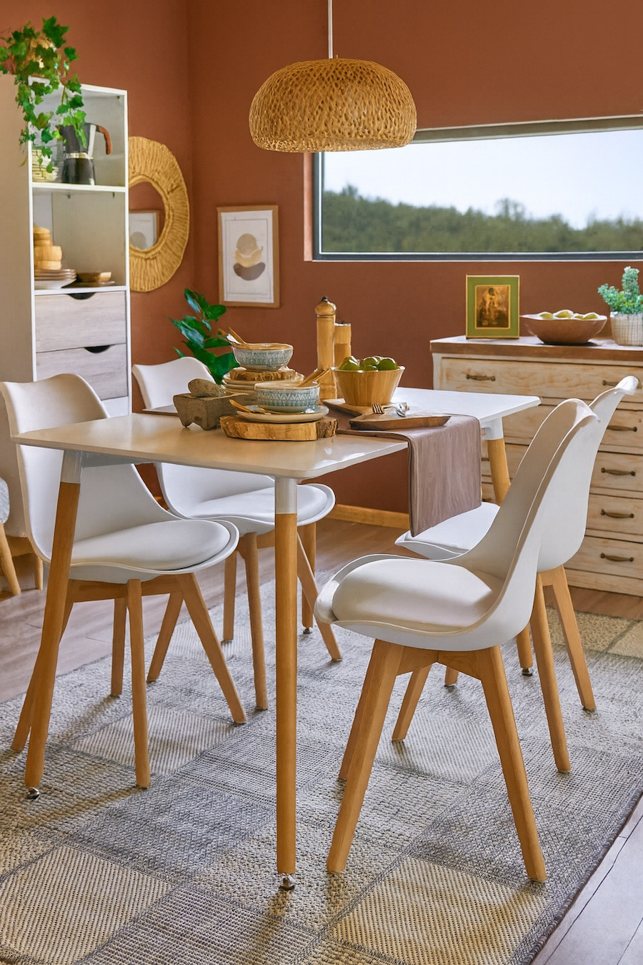Comedor cálido decorado con tonos terracota en las paredes, muebles de madera clara y fibras vegetales, ideal para interiores modernos con inspiración latinoamericana.