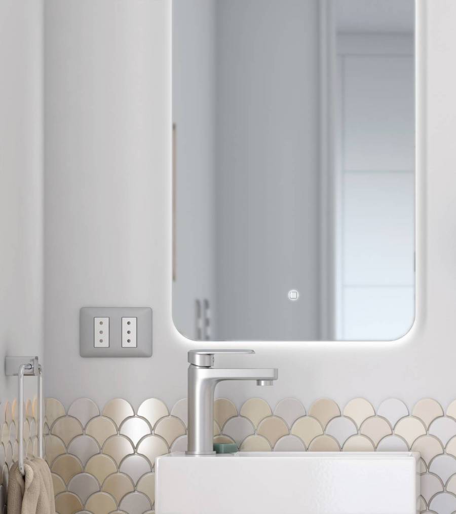 Detalle de un baño con un espejo con luces led encendido.