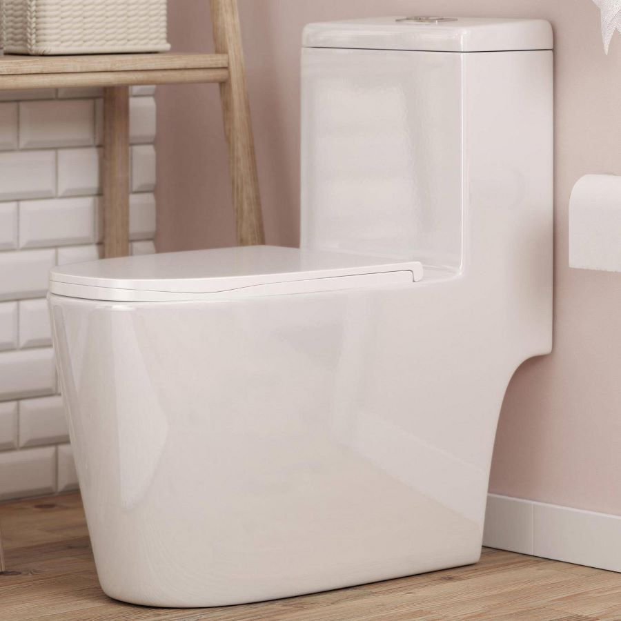 Detalle de inodoro de loza blanco, de diseño moderno, de una pieza. Muro color palo rosa y piso de madera. Un muro tiene cerámicos estilo subway color blanco. Mueble de madera clara.