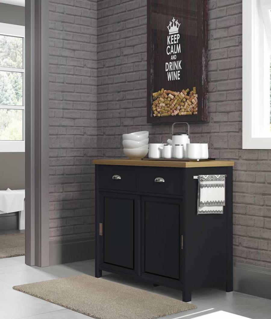 Isla de cocina negra con cubierta de madera que funciona como buffet en un comedor. Sobre ella hay tazas y pocillos blancos.