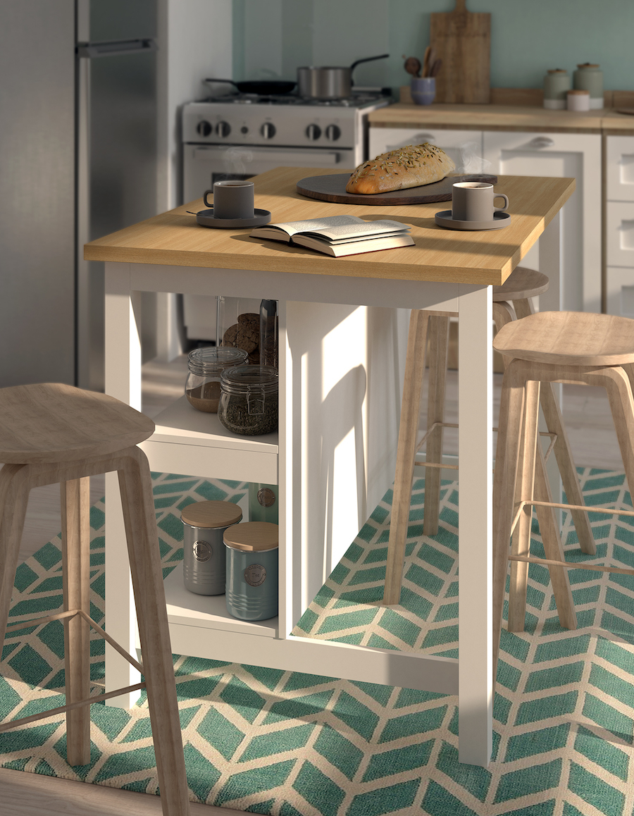 Isla de cocina de estilo nórdico, con patas y repisas blancas y cubierta de madera clara. Sobre ella hay 2 tazas de café, un pan y un libro abierto; mientras que alrededor hay 3 pisos de bar de madera. En el suelo hay una alfombra verde con líneas blancas.