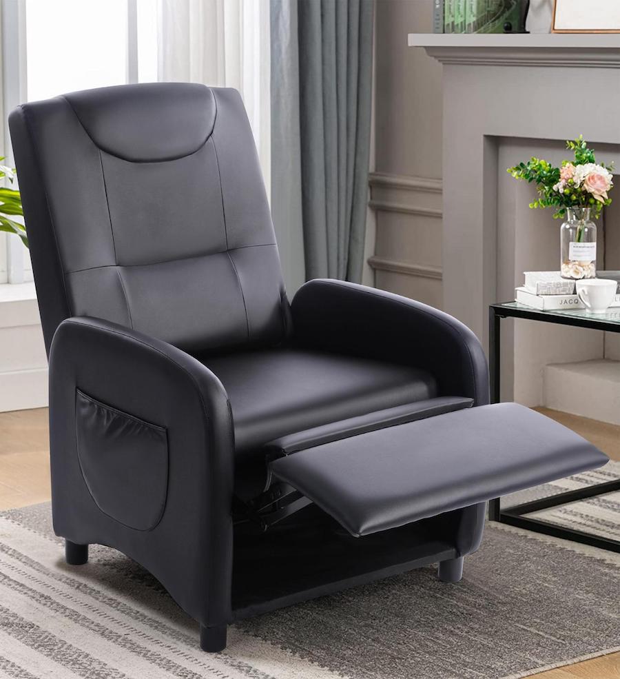 Berger plegable que se convierte en pouf. Es negro, de ecocuero y se ve abierto en su totalidad. Está en un living clásico, junto a una mesa de apoyo cuadrada con base metálica negra