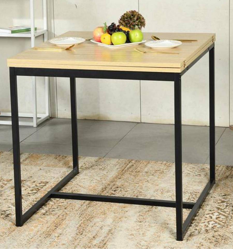 Mesa cuadrada de estructura metálica negra y cubierta de madera. Sobre ella hay un frutero, 2 platos blancos y cubiertos.