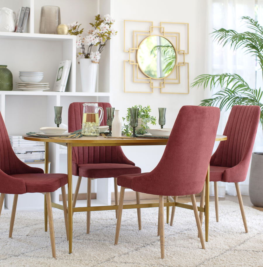 Comedor estilo clásico. Mesa rectangular, de madera, acompañada de 4 sillas con tapiz vino tinto. Bajo el comedor hay una alfombra beige. Gran repisa en el muro, con adornos y junto a ella hay un espejo dorado cuadrado.