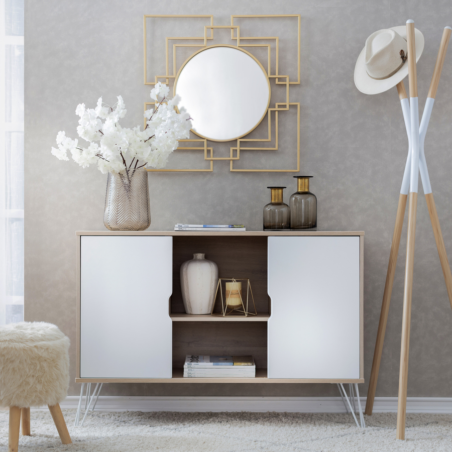 Sector de un living. Muro gris, delante de él hay un arrimo con dos puertas laterales blancas y al centro un espacio con una repisa central. Sobre el mueble hay dos botellas de vidrio y un florero. Al costado un perchero de madera y en el muro un espejo