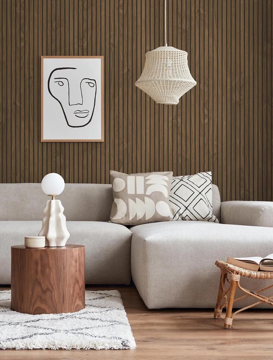 Living moderno con sofá beige y paneles decorativos de madera color nogal oscuro, acompañado de una lámpara tejida y decoración en tonos neutros.