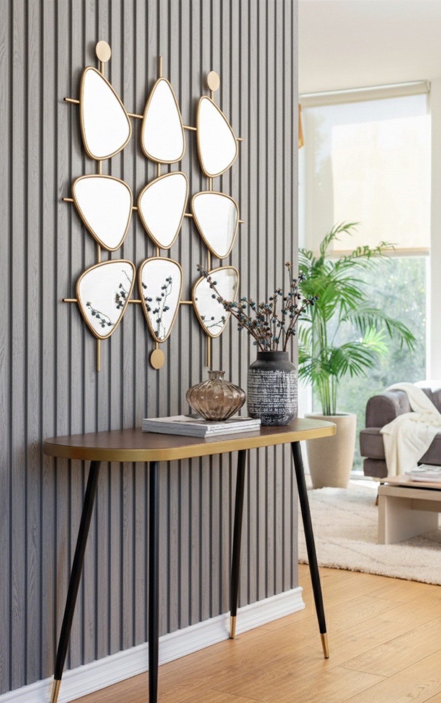 Entrada elegante con panel de madera gris, arrimo de patas largas y delgadas negras y espejos decorativos con marco dorado sobre el panel.