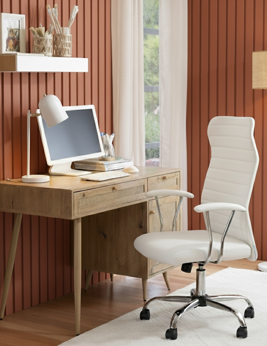 Oficina en casa con panel decorativo terracota, escritorio rústico y silla blanca frente a una ventana con visillo blanco.