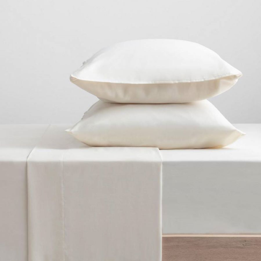 Juego de sábanas blancas con dos almohadas con fundas blancas