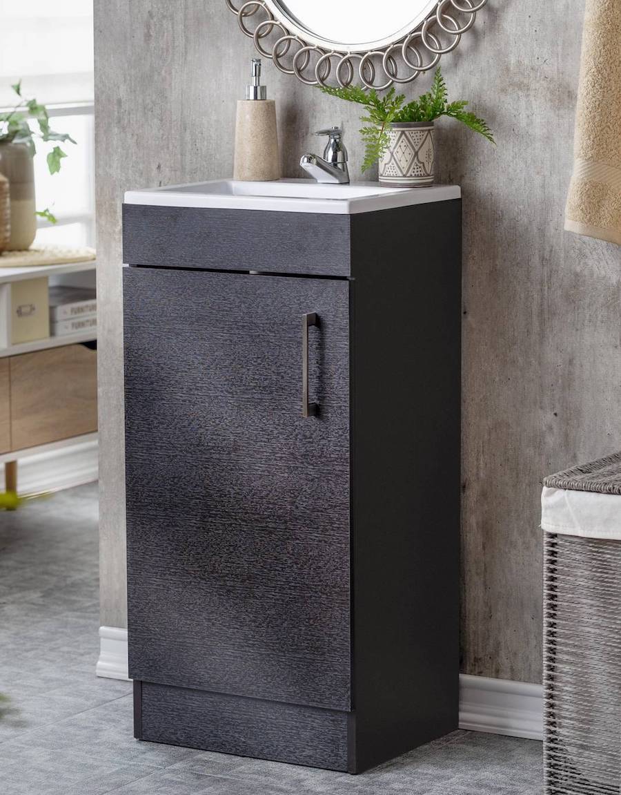 Baño de muro de concreto con un mueble vanitorio rectangular negro con lavamanos blanco y grifería plateada.